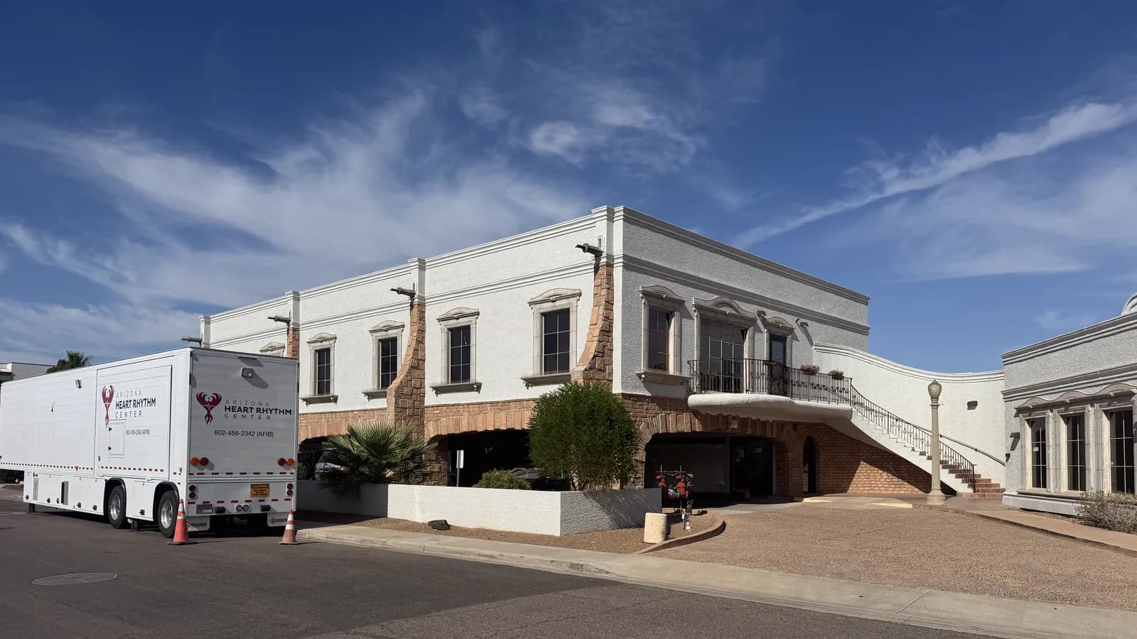 The entrance elevation of the center. A covered drive runs under the building's first floor to a shaded doorway, so a patient can be dropped off out of the sun, with the exterior staircase and balcony above it.