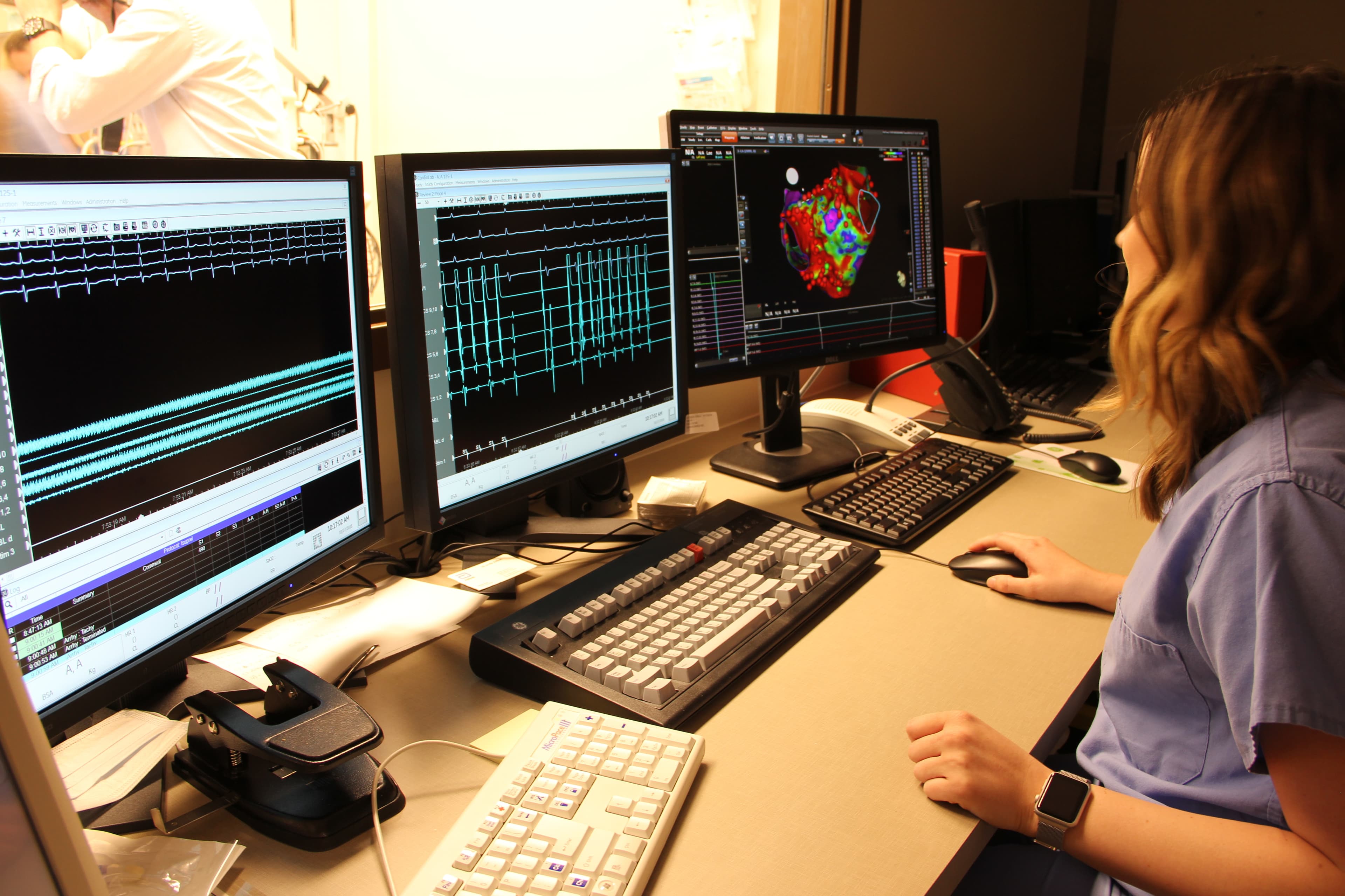 A team member at the monitoring workstation, viewing heart rhythm recordings and a three-dimensional cardiac map on multiple displays.